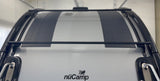 Top view of a nüCamp RV rental's roof, showing integrated solar panels and a black roof rack system.