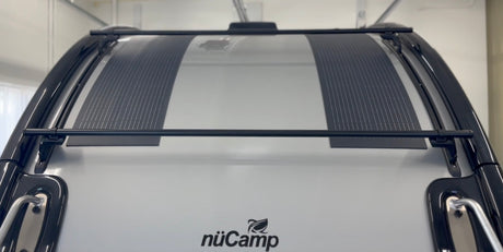 Top view of a nüCamp RV rental's roof, showing integrated solar panels and a black roof rack system.