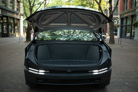 Rear view of dark, modern vehicle with trunk open, showing spacious cargo & bright LED lights. Great for your next RV rental trip.