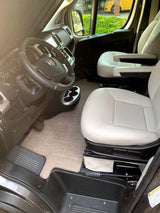 Spacious RV rental interior with light-colored driver/passenger seats, steering wheel, dashboard, and floor mat.
