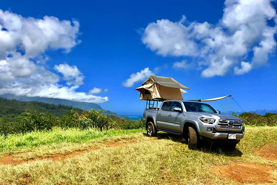 An RV rental alternative: silver pickup truck with rooftop tent and awning on a scenic mountain-ocean view. — photo 2