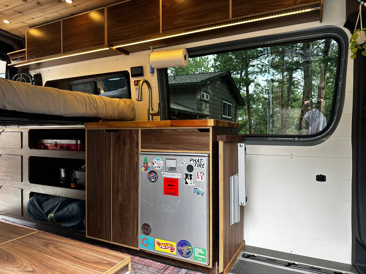 Explore this custom rv rental's interior, featuring a chic kitchenette, overhead storage, and comfortable sleeping area. — photo 13