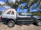 Grey Toyota Tacoma with a truck bed tent setup, a versatile camping option for outdoor adventures, like an RV rental.