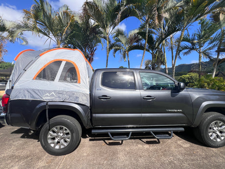 Grey Toyota Tacoma with a truck bed tent setup, a versatile camping option for outdoor adventures, like an RV rental.