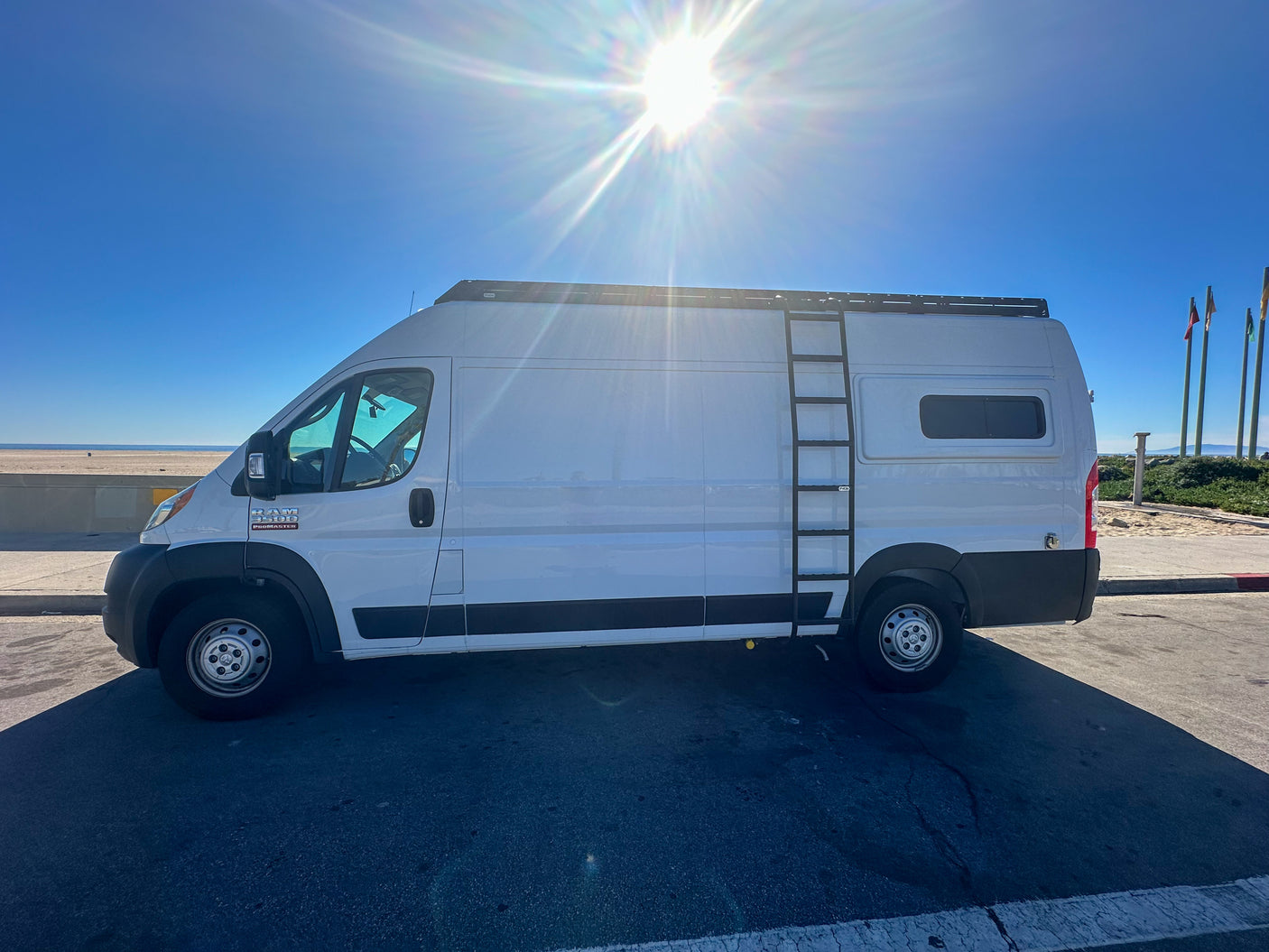 Bright sunny day for a white Ram ProMaster **rv rental** on the beachfront. Perfect for **van life** adventures & **travel**.
