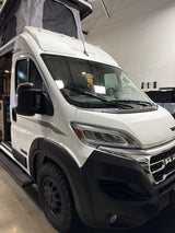 A sleek white Winnebago camper van, based on a Ram ProMaster chassis, featuring a pop-top roof. Ideal for rv rental adventures!
