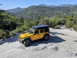 Yellow Jeep Wrangler Rubicon with rooftop tent on a scenic mountain off-road trail. Perfect for RV rental adventures!