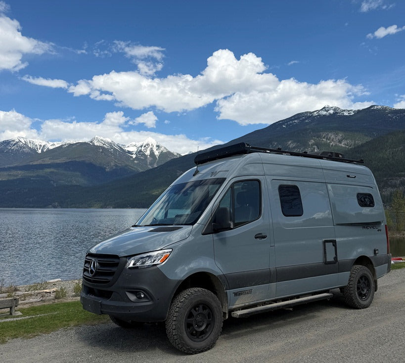 Gray Winnebago Revel camper van, perfect for an rv rental adventure by a scenic lake and snow-capped mountains.
