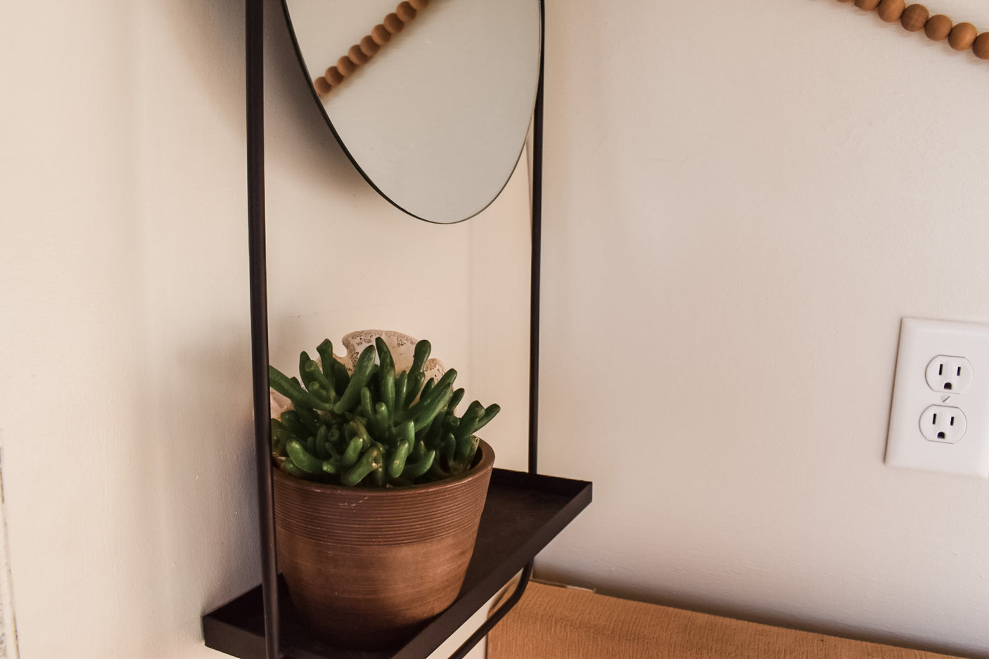 Cozy RV rental interior with a succulent on a wall shelf and a mirror, featuring a functional power outlet.
