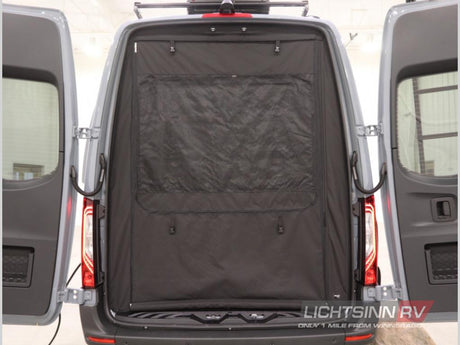 Rear view of an RV rental van with open back doors and a black fabric interior screen, showing cargo space.