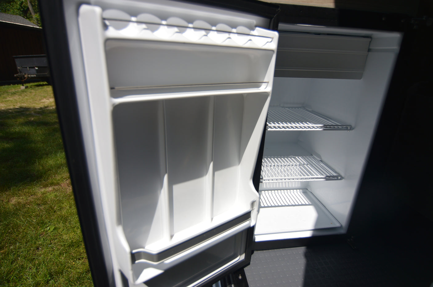 Open, clean, empty refrigerator in an RV rental, with multiple shelves. Ready for your adventure.