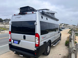 An Entegra Ethos camper van, an excellent rv rental option, parked on a dirt path along a coastal road.