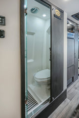 An RV rental's clever compact bathroom design features a toilet, shower, and a space-saving sliding door.