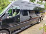Side view of a glossy black luxury Sprinter van, ideal for rv rental. Parked on concrete with tinted windows and cream seats.