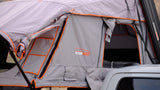 Open gray and orange Roofnest rooftop tent on a white vehicle, ideal for your next RV rental camping trip.