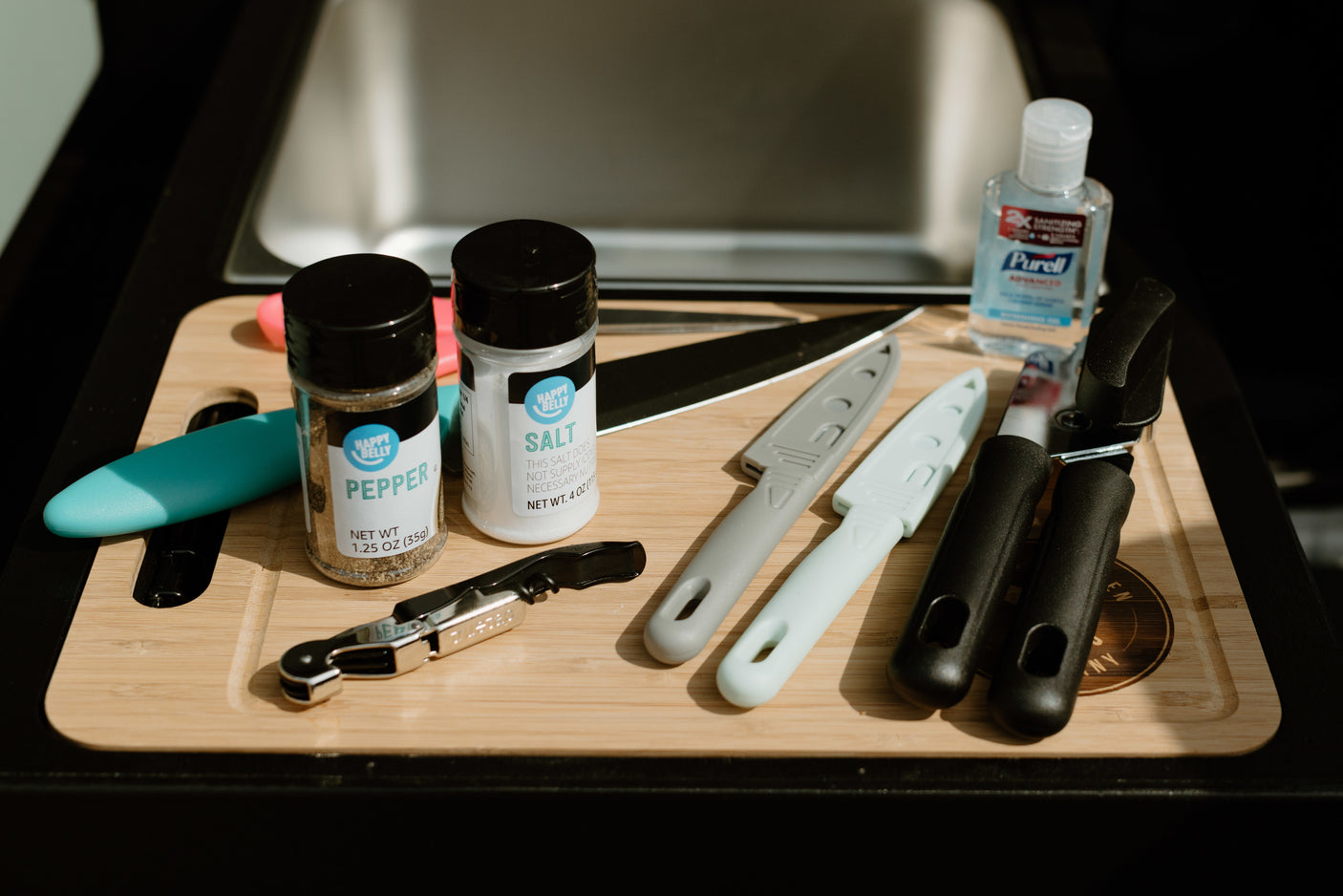 Compact kitchen setup for your rv rental: salt, pepper, knives, corkscrew & Purell on a cutting board.