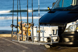 An RV rental van equipped for a beach fishing trip, with rods, cooler, and firewood on its front carrier.