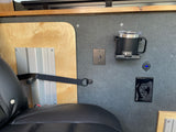 RV rental interior: Plywood and gray wall panels, a black seat, power/USB outlets, Yeti mug holder, and a control knob.