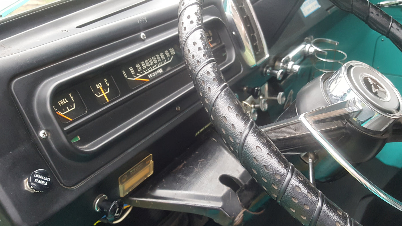 Glimpse of a classic RV rental's dashboard: gauges, steering wheel, and emergency flasher, showing mileage.