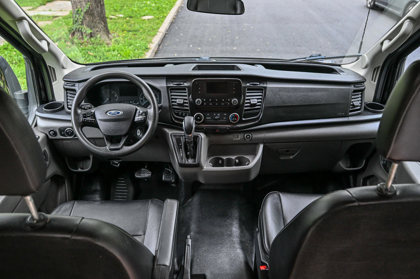 Front cabin of an RV rental van, showcasing the dashboard, steering wheel, and seating area from an elevated view.