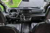 Front cabin of an RV rental van, showcasing the dashboard, steering wheel, and seating area from an elevated view.