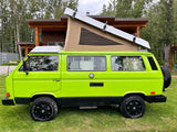Bright green VW Vanagon camper van with pop-top roof and rugged tires, ready for RV rental adventures.
