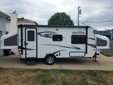 A white Spree Escape hybrid travel trailer (RV rental) is set up in a residential driveway.