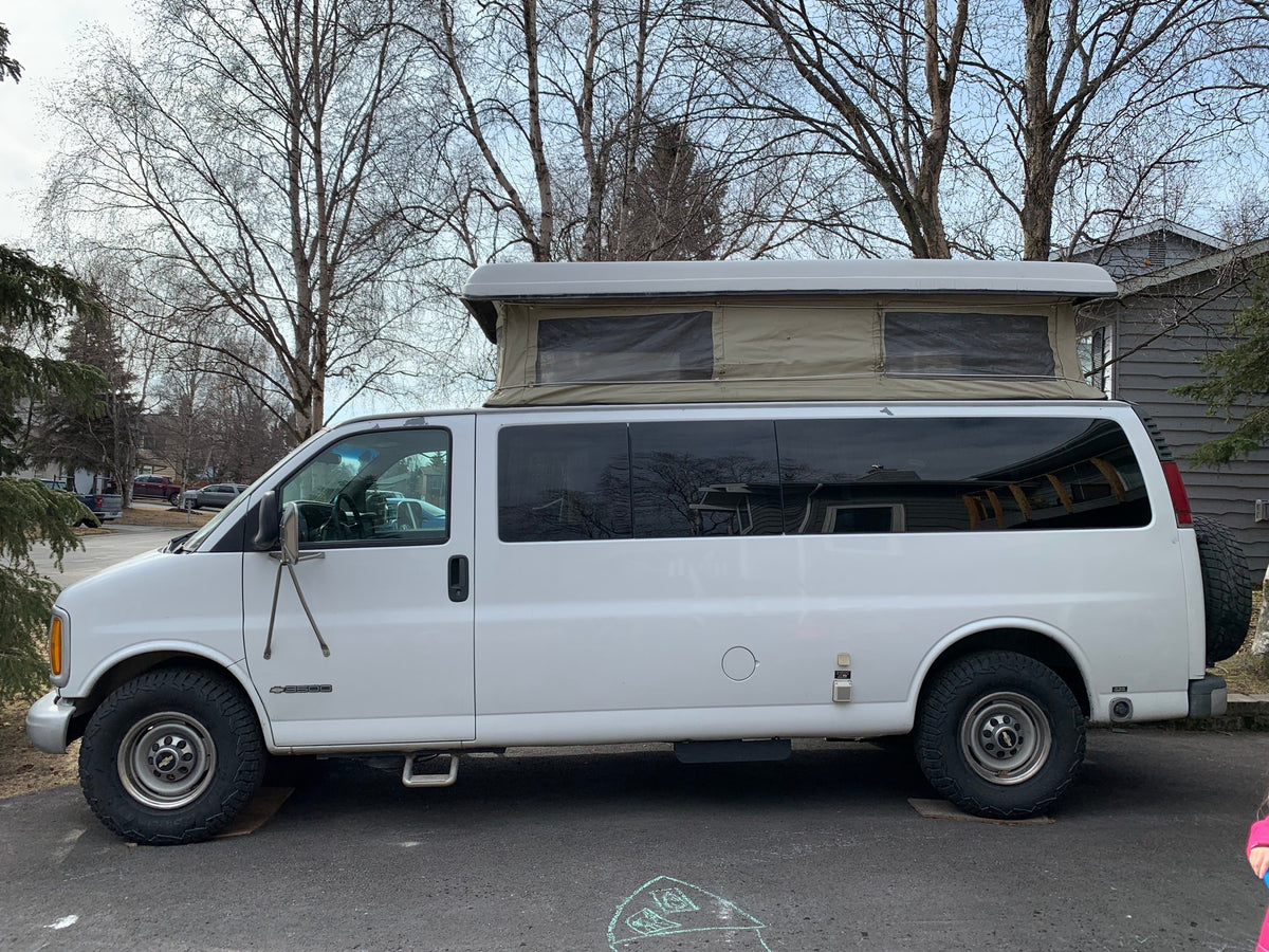 A white Chevrolet Express camper van with a pop-top roof, suitable for rv rental and outdoor adventures.