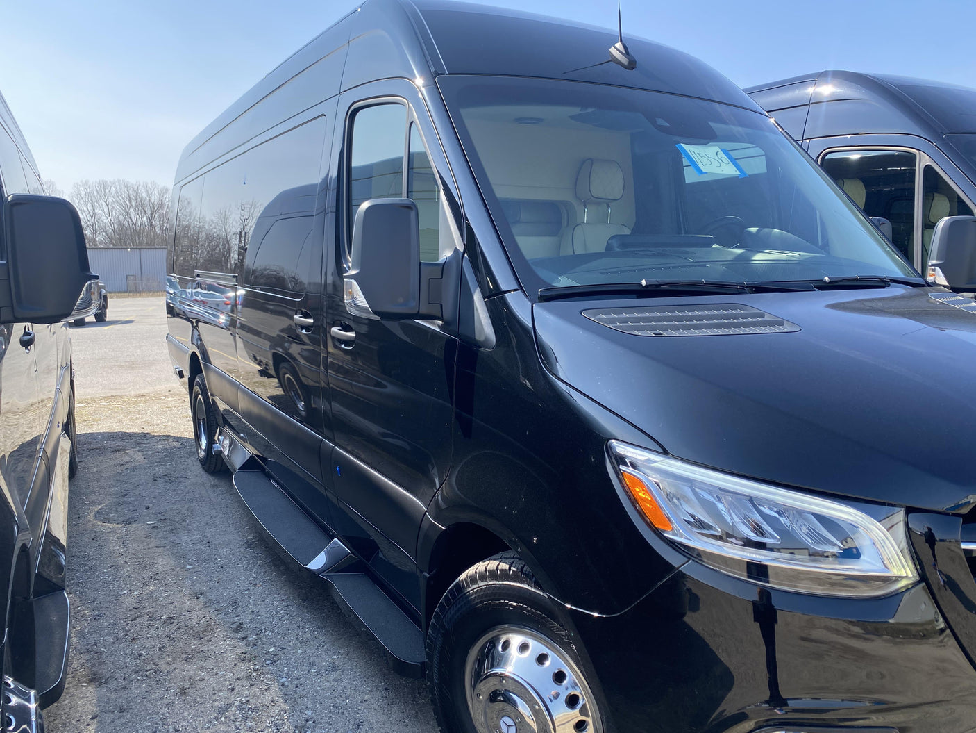 A black Mercedes-Benz Sprinter conversion van, perfect for rv rental, parked on a sunny day. Interior seats visible.