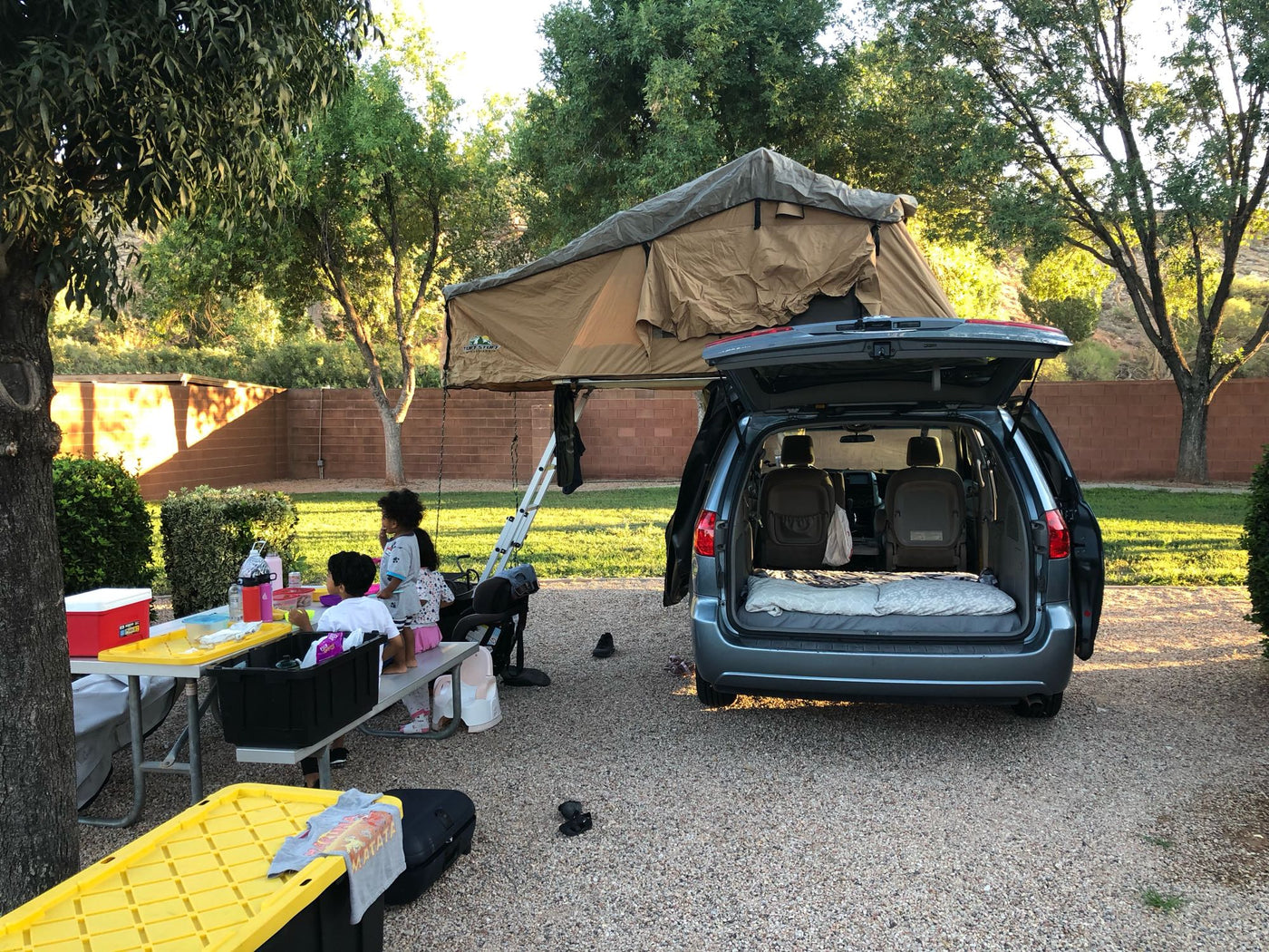  an RV rental option for family camping. Children are at a picnic table nearby.|RV rental campsite cooking: Coleman stove on a portable table with a pot on gravel — photo 9