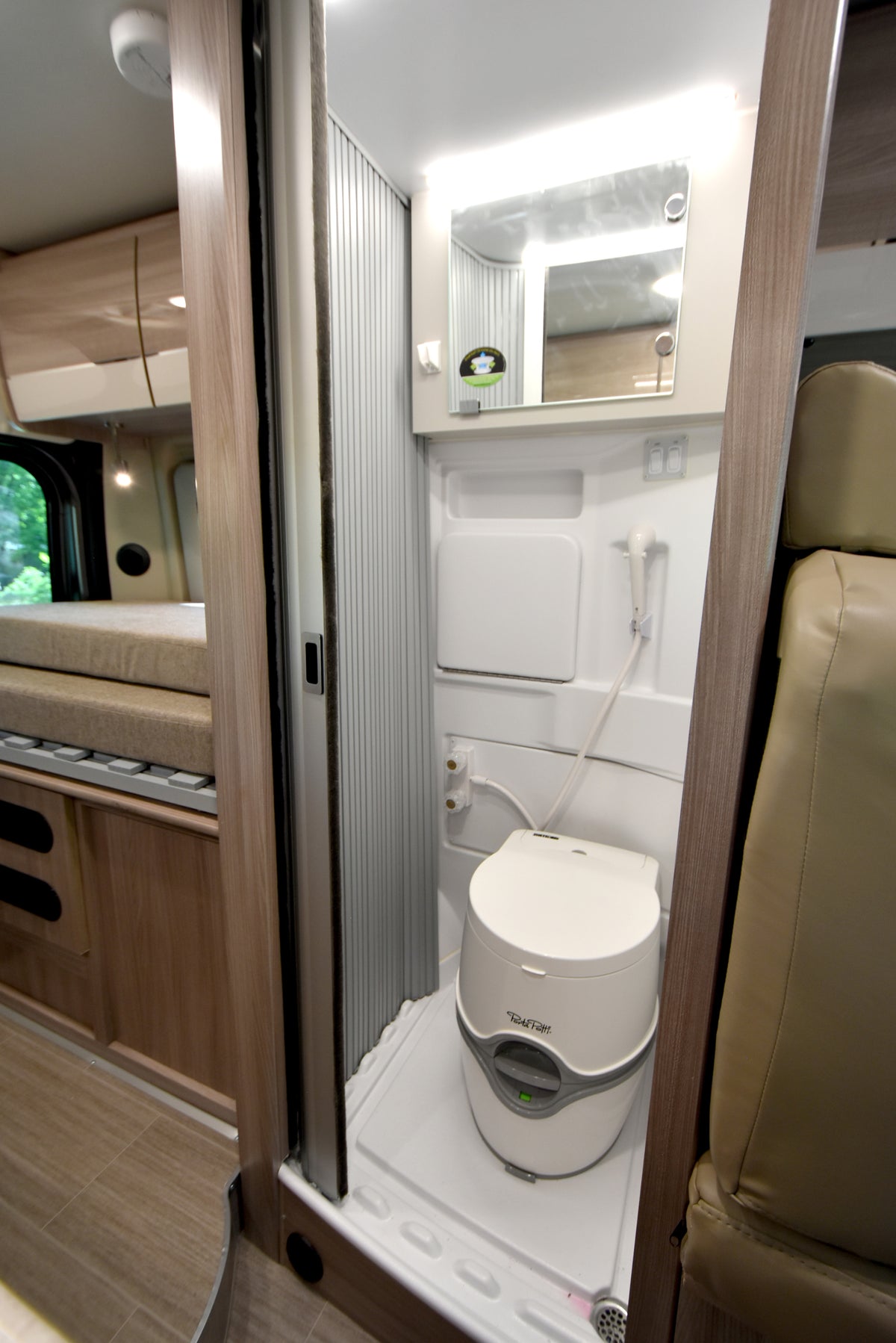 Spacious rv rental interior shows swivel seats, dashboard, and a tranquil lake view for comfortable travel. — photo 7