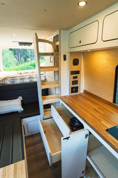 Spacious and modern RV rental interior featuring a bed, ladder, kitchenette, and ample storage, perfect for your next adventure.