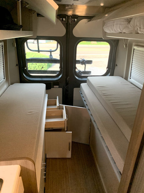RV rental interior: cozy camper van with flexible beds & pull-out storage, perfect for mobile travel.