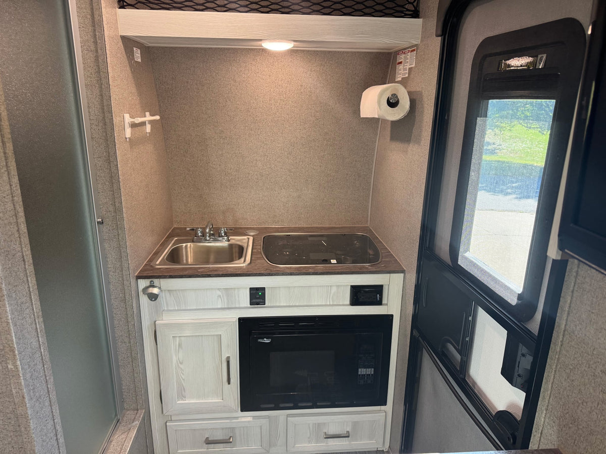  parked on gravel for your next camping adventure.|A sleek white and green Flagstaff E-Pro travel trailer sits on gravel — photo 7