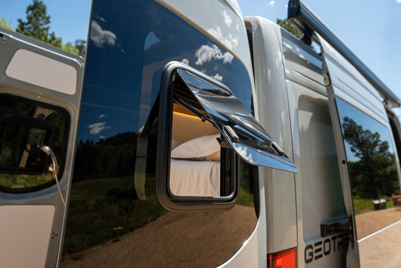 Open window of an RV rental reveals a cozy bed inside a light-colored camper van, ready for adventure. — photo 17