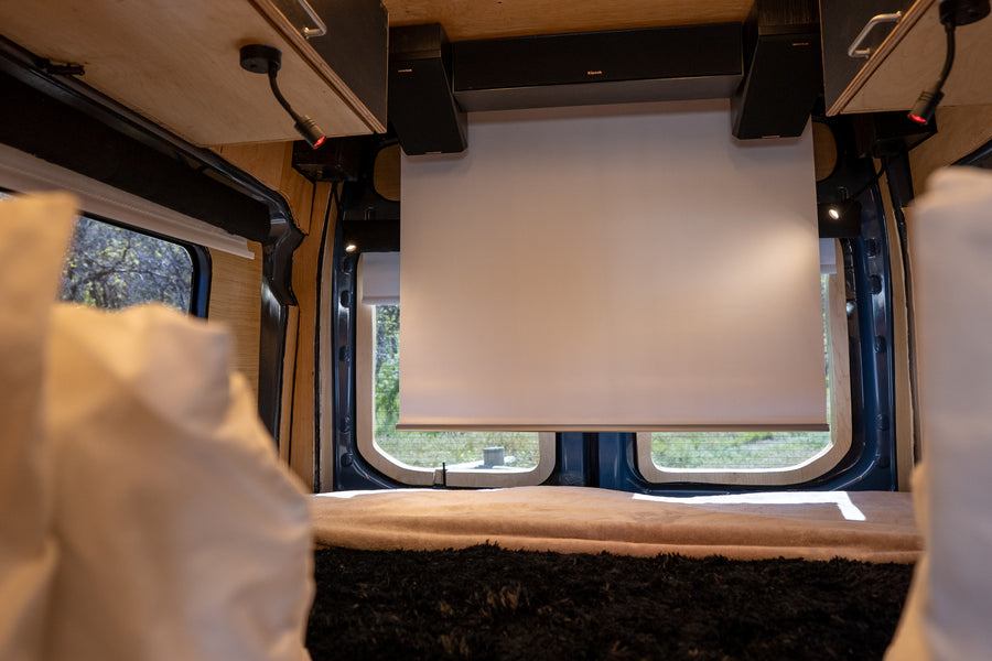Experience an RV rental! Van interior with a pull-down screen, speakers, and comfy bed for a cozy mobile entertainment setup.