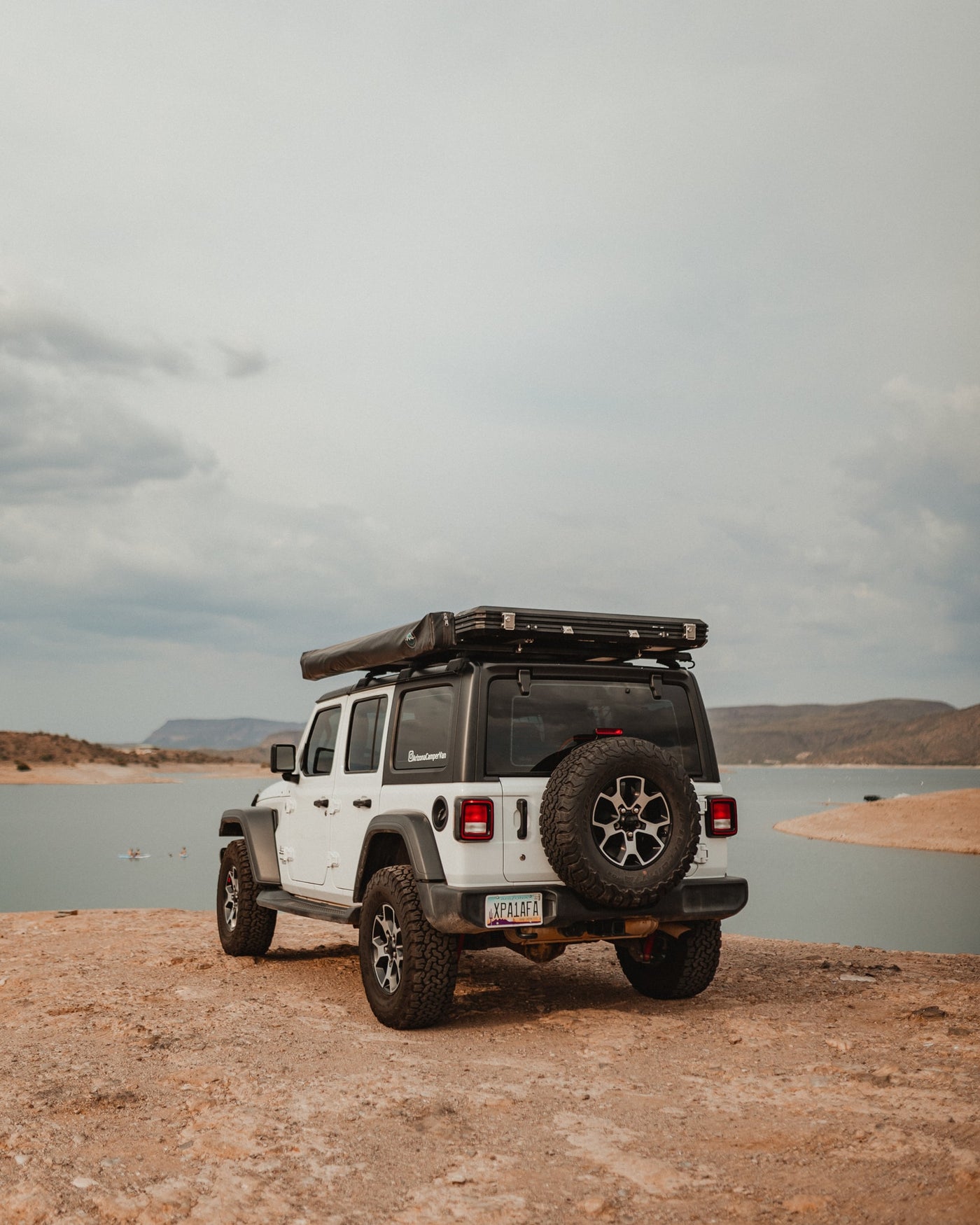 Adventure-ready white Jeep Wrangler RV rental with rooftop tent by a scenic lake, perfect for overlanding excursions. — photo 7