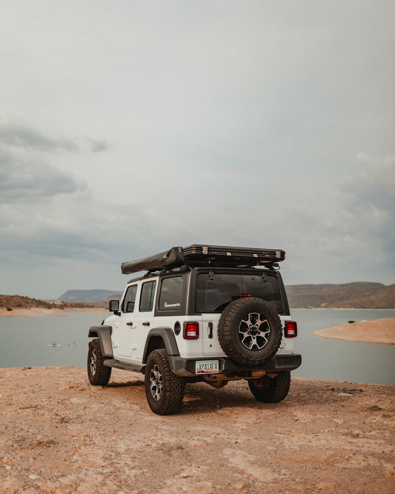 Adventure-ready white Jeep Wrangler RV rental with rooftop tent by a scenic lake, perfect for overlanding excursions. — photo 7