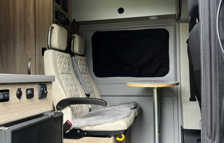 RV rental interior: passenger seats, table, and power controls for comfortable travel.