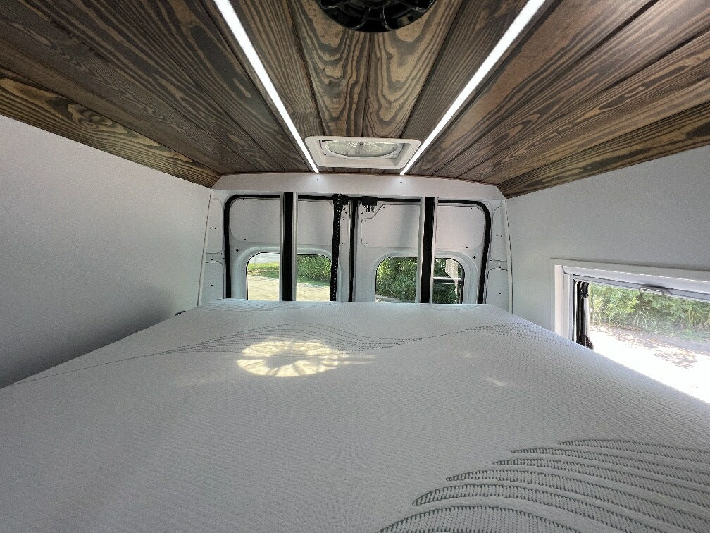 Inside this RV rental, find a comfy bed, a stylish wooden ceiling with LED lights, and views from rear windows.