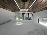 Inside this RV rental, find a comfy bed, a stylish wooden ceiling with LED lights, and views from rear windows.