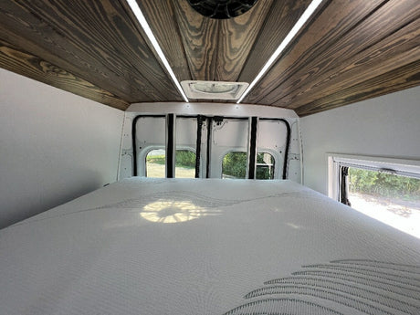 Inside this RV rental, find a comfy bed, a stylish wooden ceiling with LED lights, and views from rear windows.