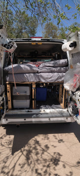 Rear view of a cozy camper van interior with bed, toilet, and water tank, perfect for an rv rental adventure.