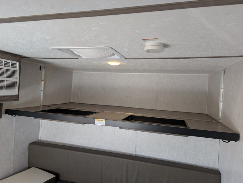 RV rental bunk bed setup in camper interior. Features covered storage bins, AC, and safety devices like a smoke detector. — photo 14