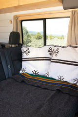Enjoy comfort on your RV rental journey. Plush pillows & a striped blanket on the back seat, with a scenic nature view.