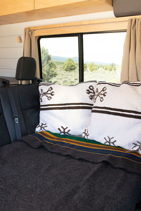 Enjoy comfort on your RV rental journey. Plush pillows & a striped blanket on the back seat, with a scenic nature view.