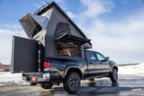 Explore the outdoors! This black pickup truck features a pop-up rooftop tent and truck camper, ideal for RV rental adventures.