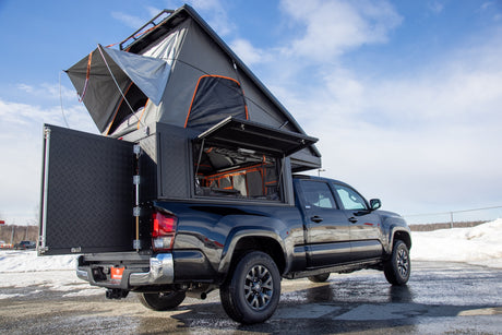 Explore the outdoors! This black pickup truck features a pop-up rooftop tent and truck camper, ideal for RV rental adventures.