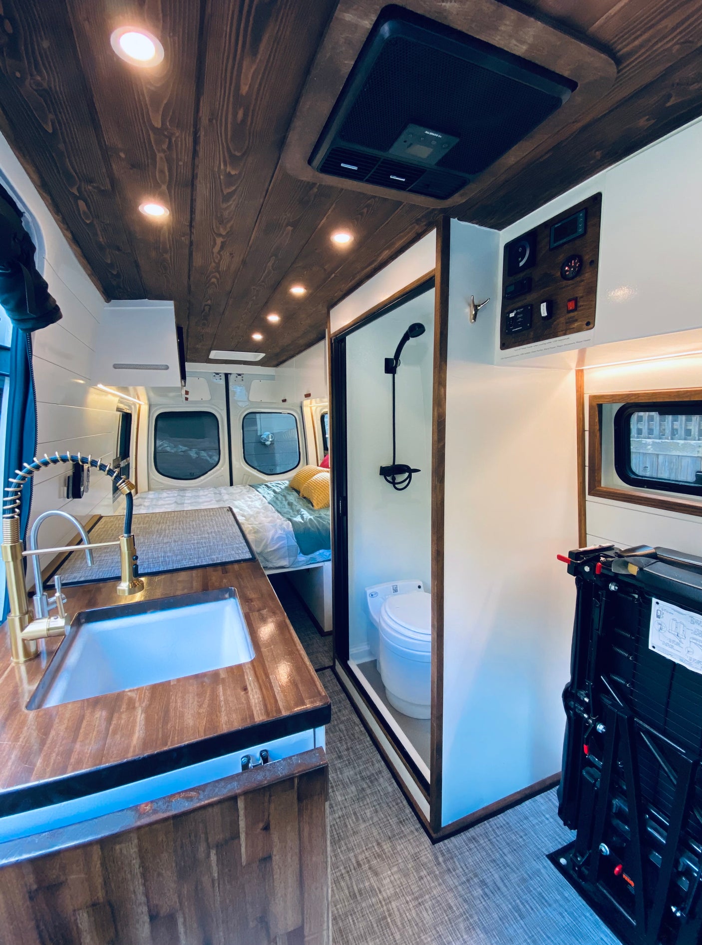 Step inside this stylish RV rental, showcasing a functional kitchen, comfortable bed, and compact bathroom amenities.