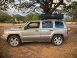 A gold Jeep Patriot SUV with a rooftop tent, ideal for RV rental trips and overland camping adventures.